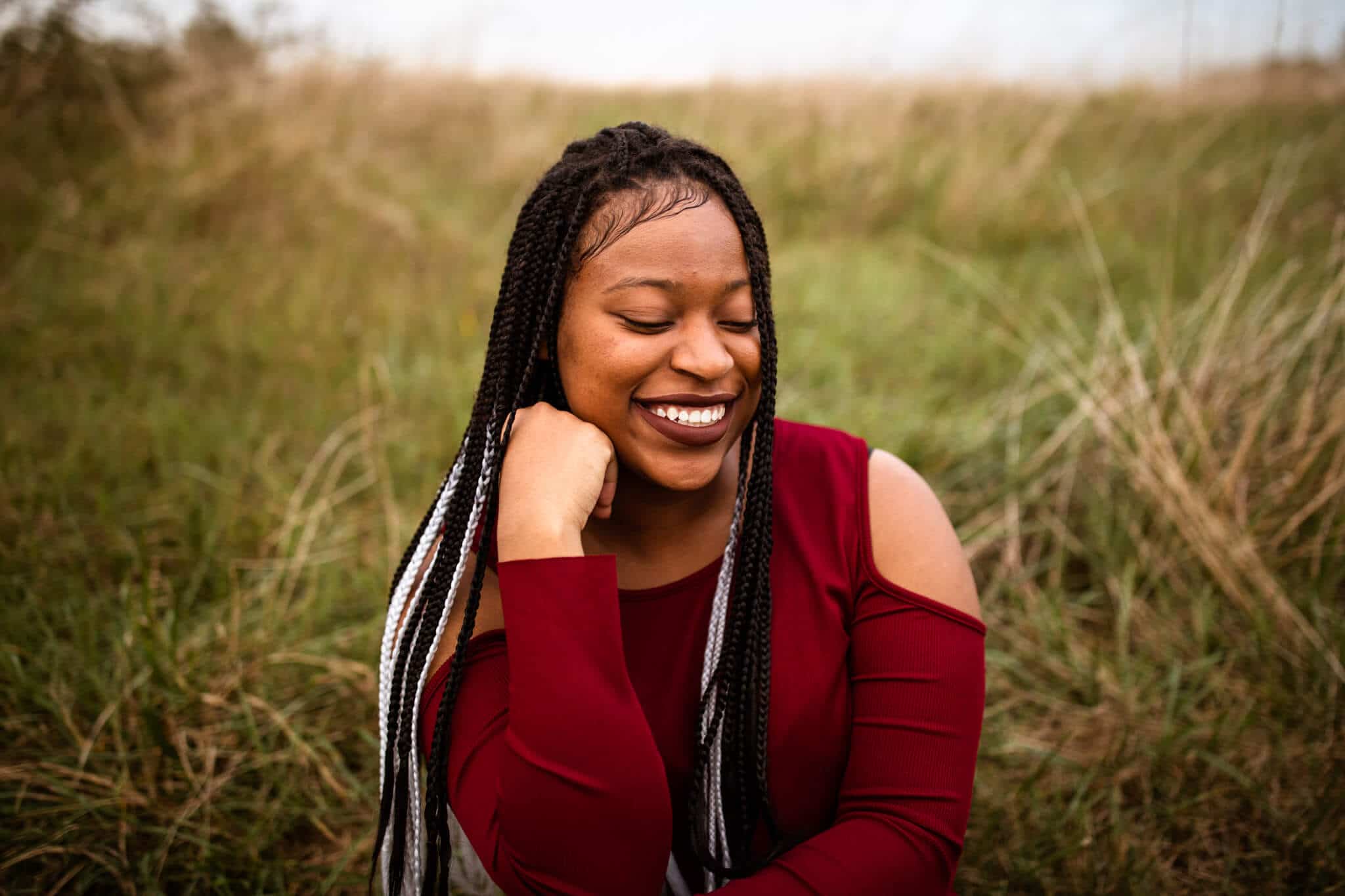 high school senior girl smiling sitting in field