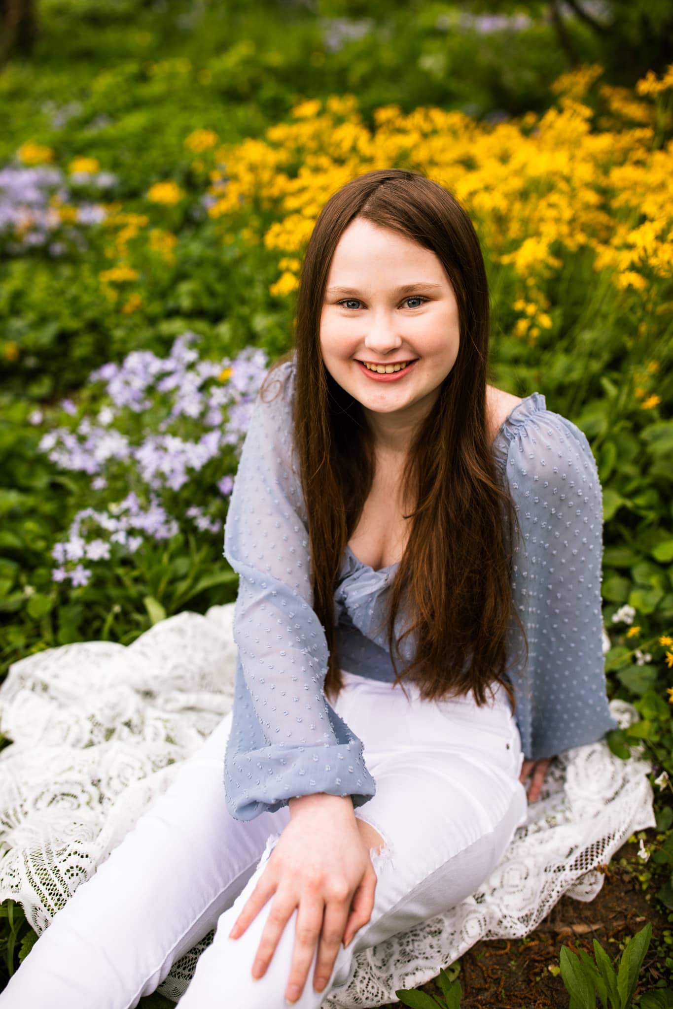 high school senior girl smiles in field of flowers
