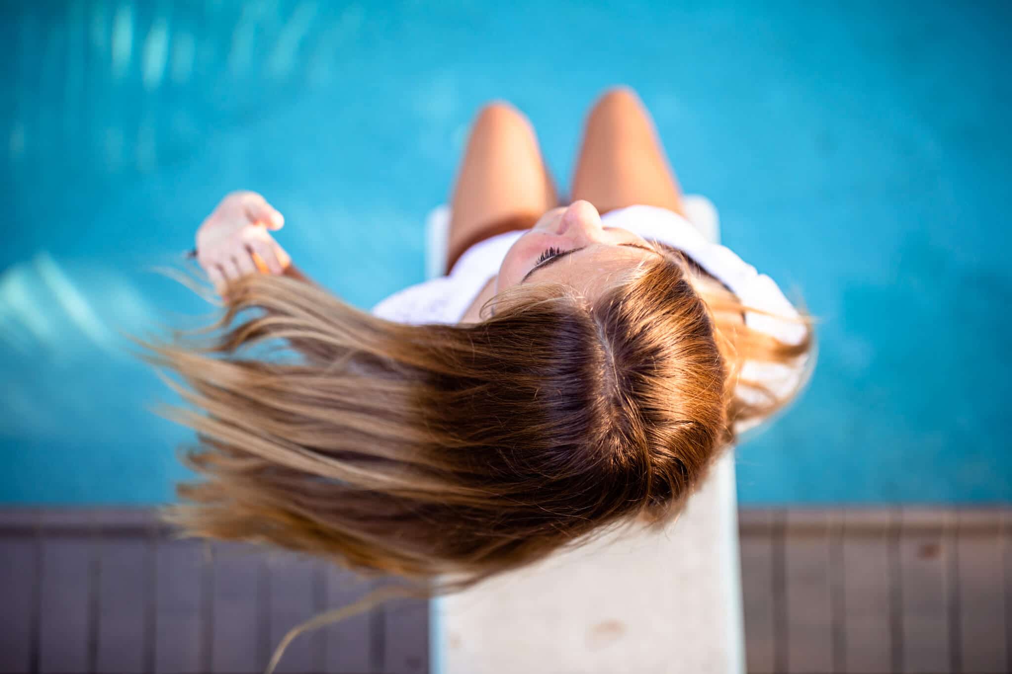 high school senior girl plays with hair above pool