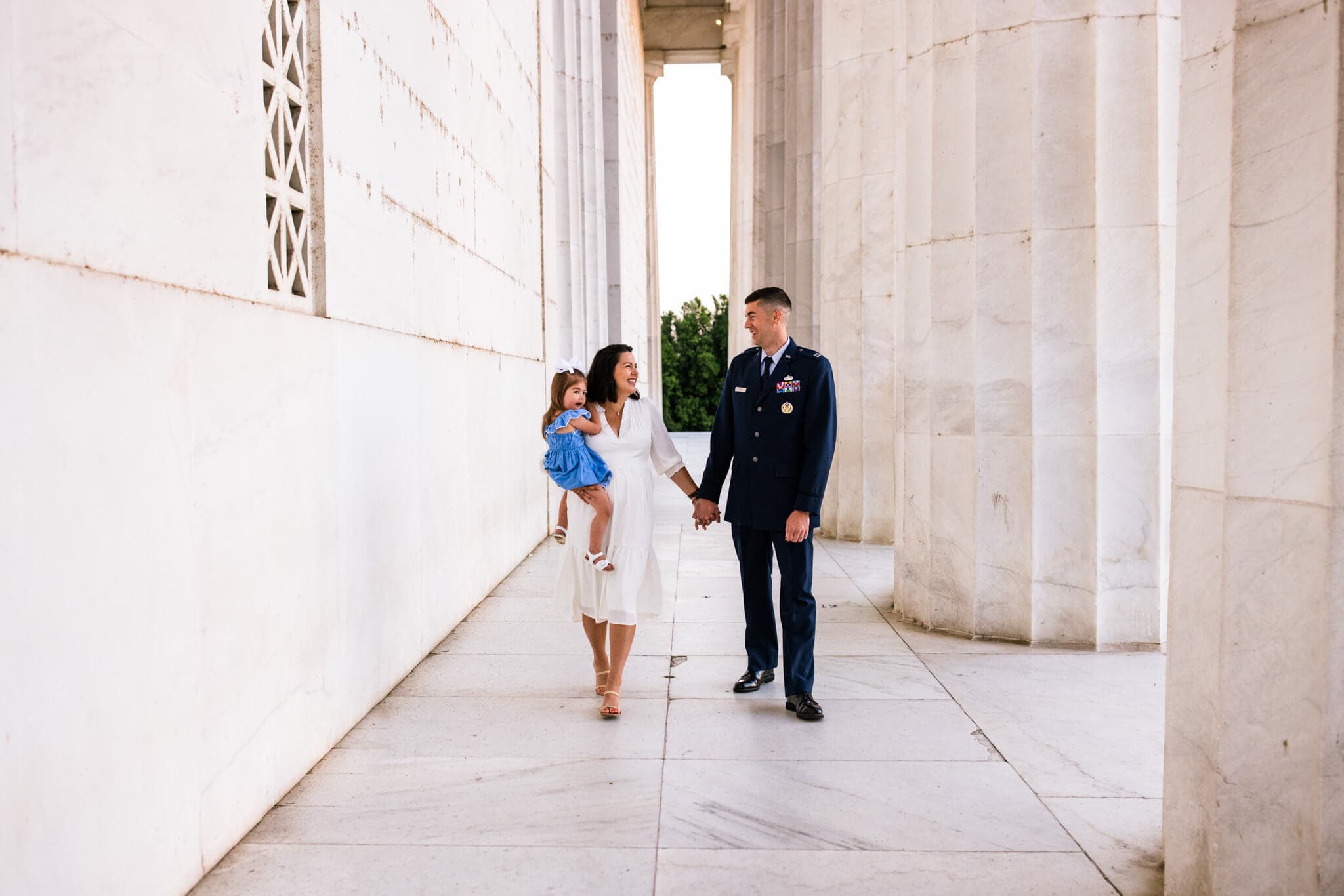 mother holds daughter and walks with husband along top of Lincoln Memorial