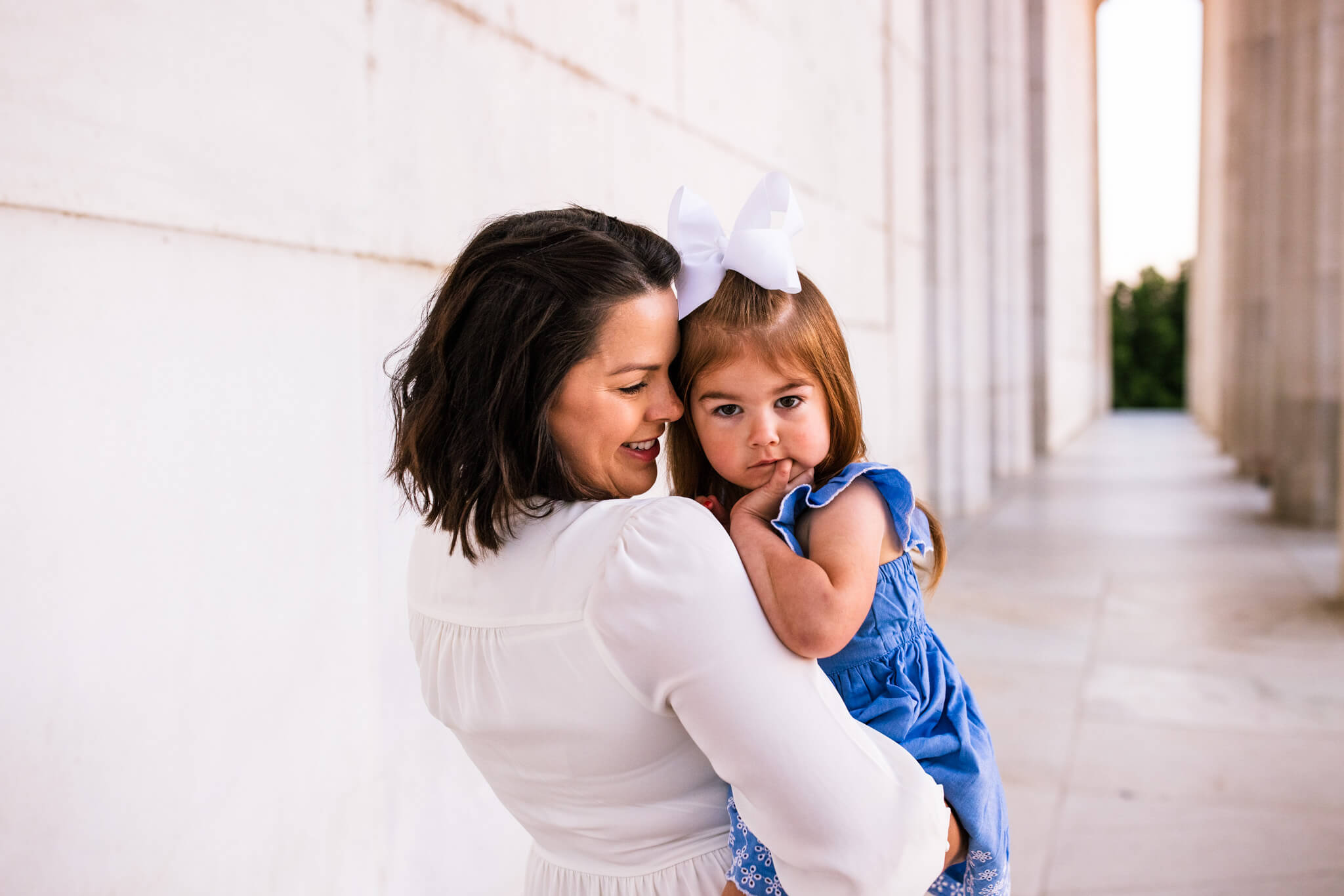 mother snuggles young daughter on Lincoln Memorial