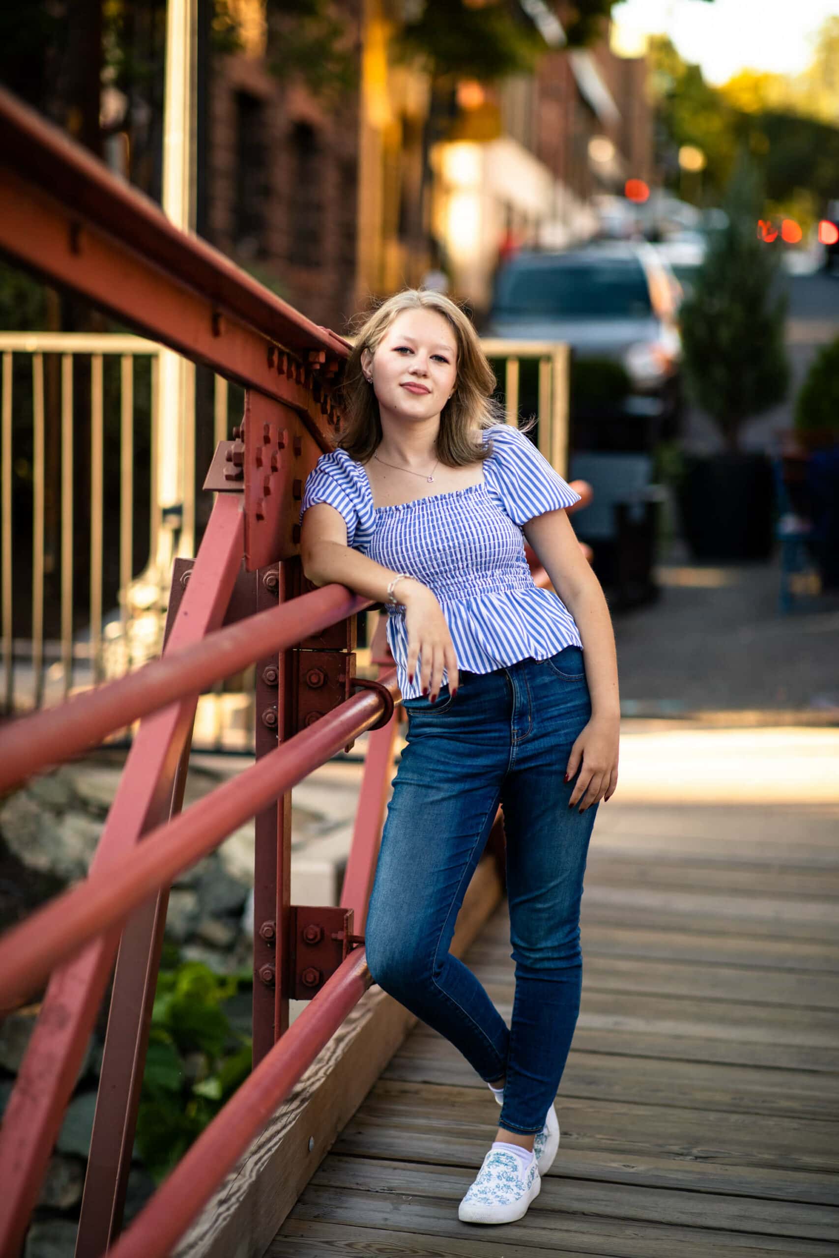 high school senior girl leaning against bridge