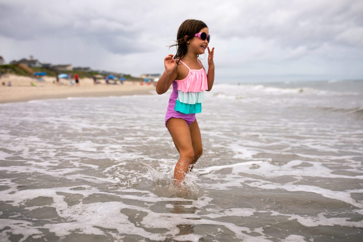 girl jumping in ocean waves on cloudy day