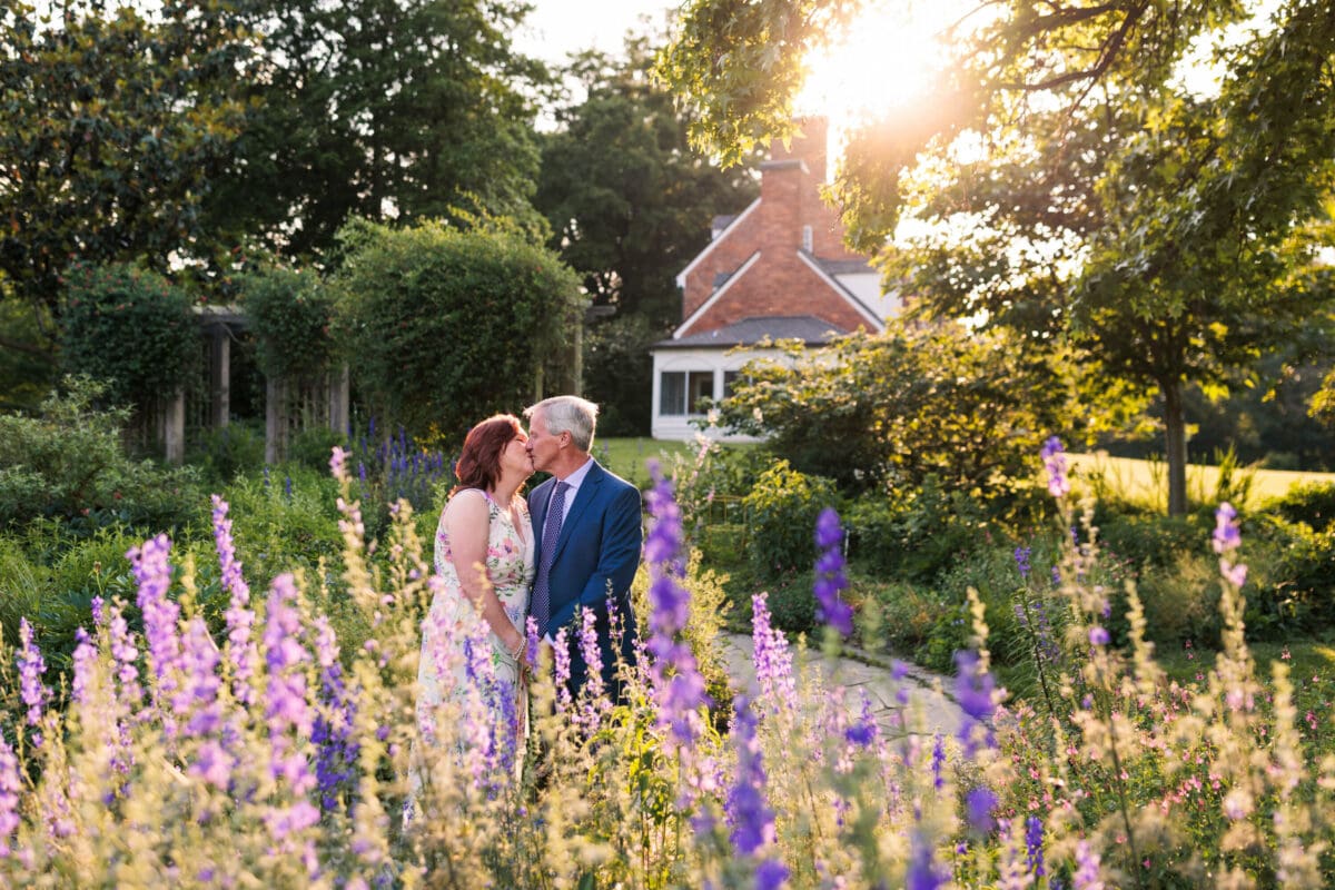 couple kissing near purple flowers with sunset