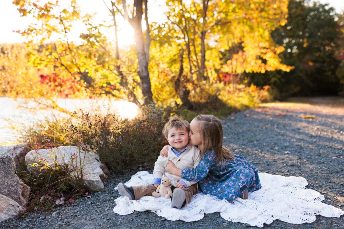 two young siblings snuggling with fall leaves