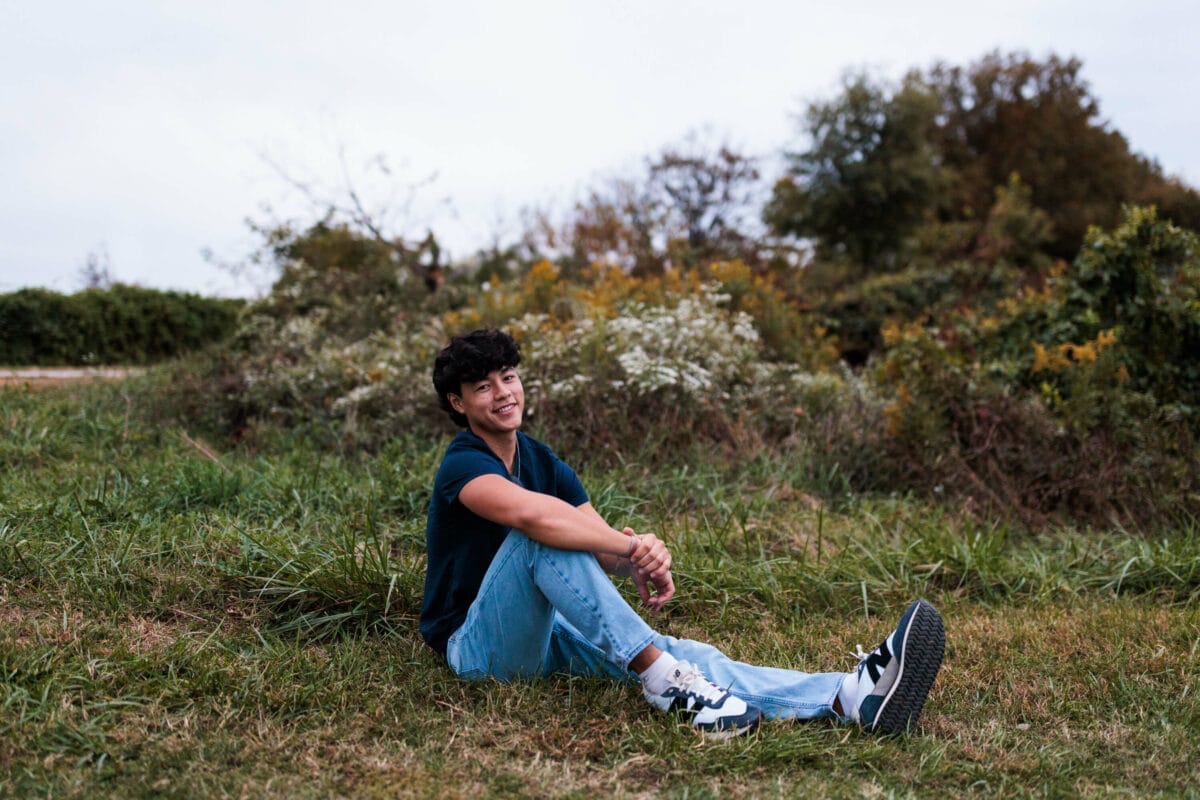 high school senior boy photo session sitting in front of flowers