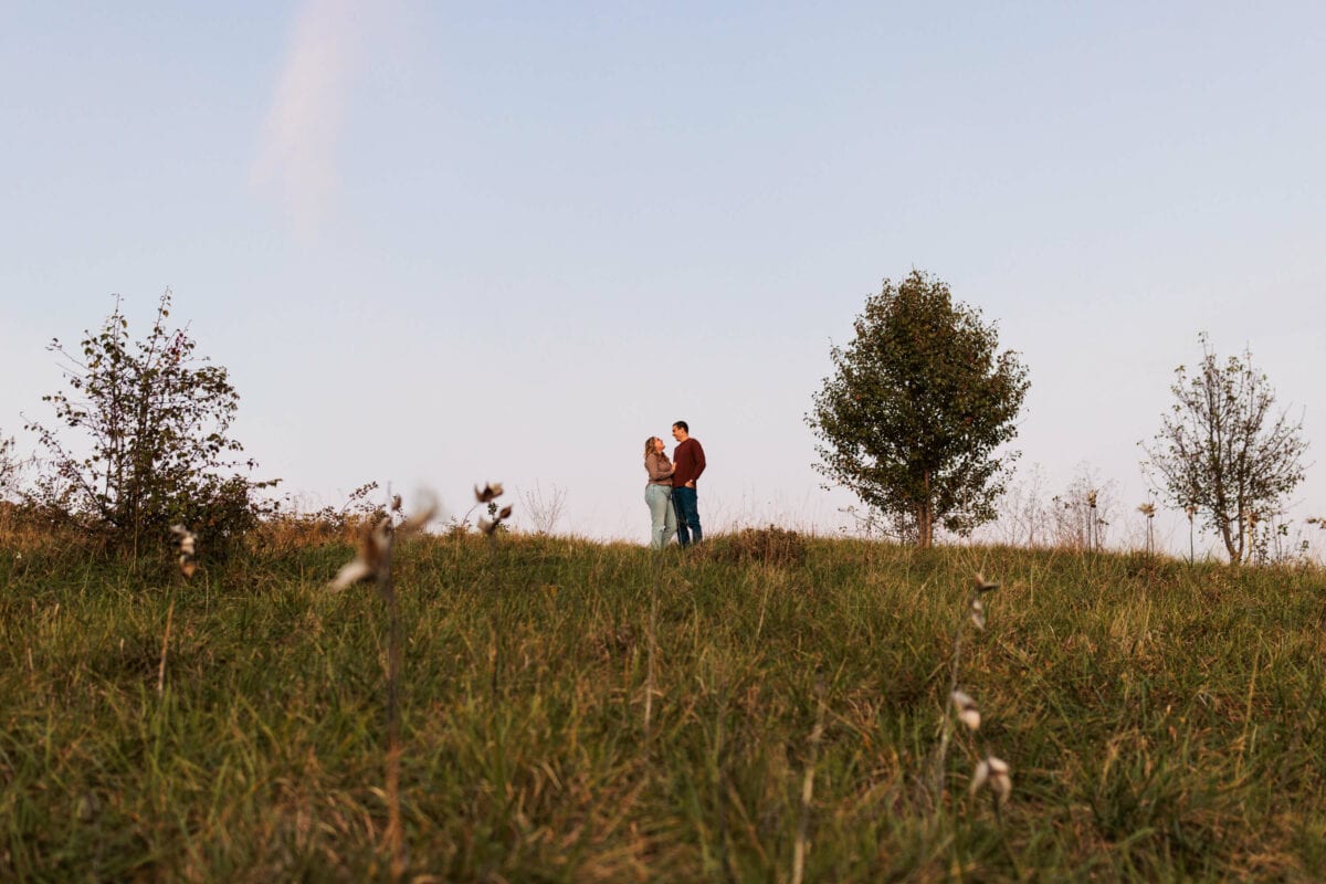 couple standing near each other at top of hill 