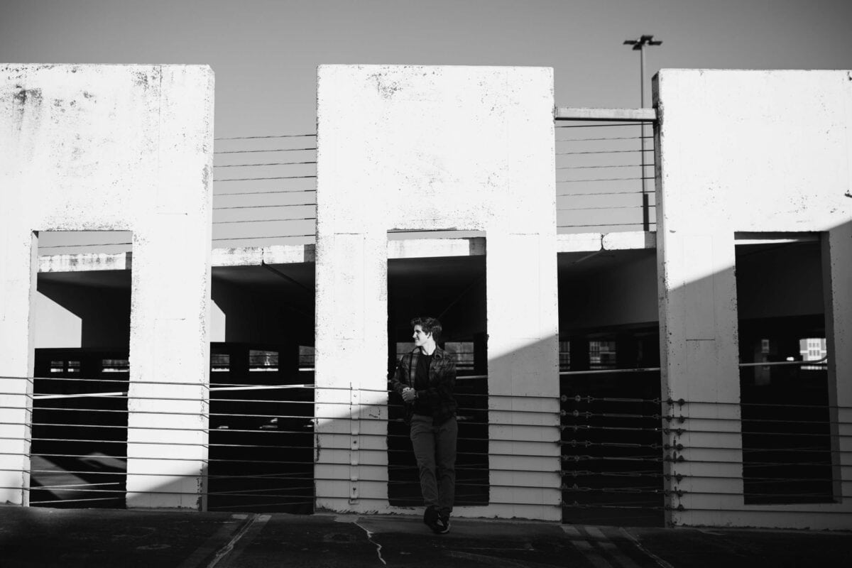 black and white image of senior boy with harsh sun and lines for inspiration for a parking garage senior session