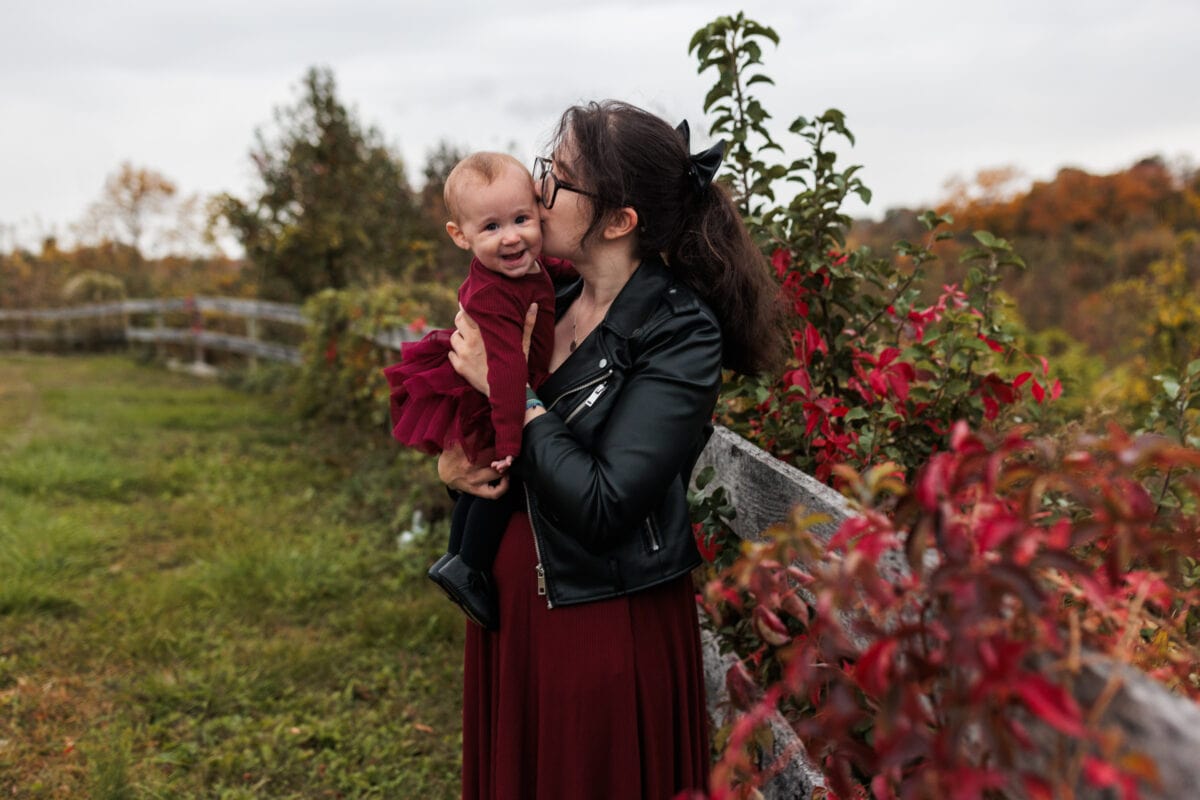 mother snuggling daughter with red leaves fall photography client superlative awards
