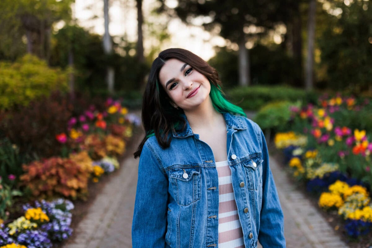 close up senior girl smiling in flower-filled garden