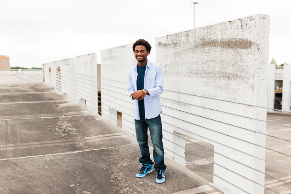 high school senior boy standing near parking garage wall