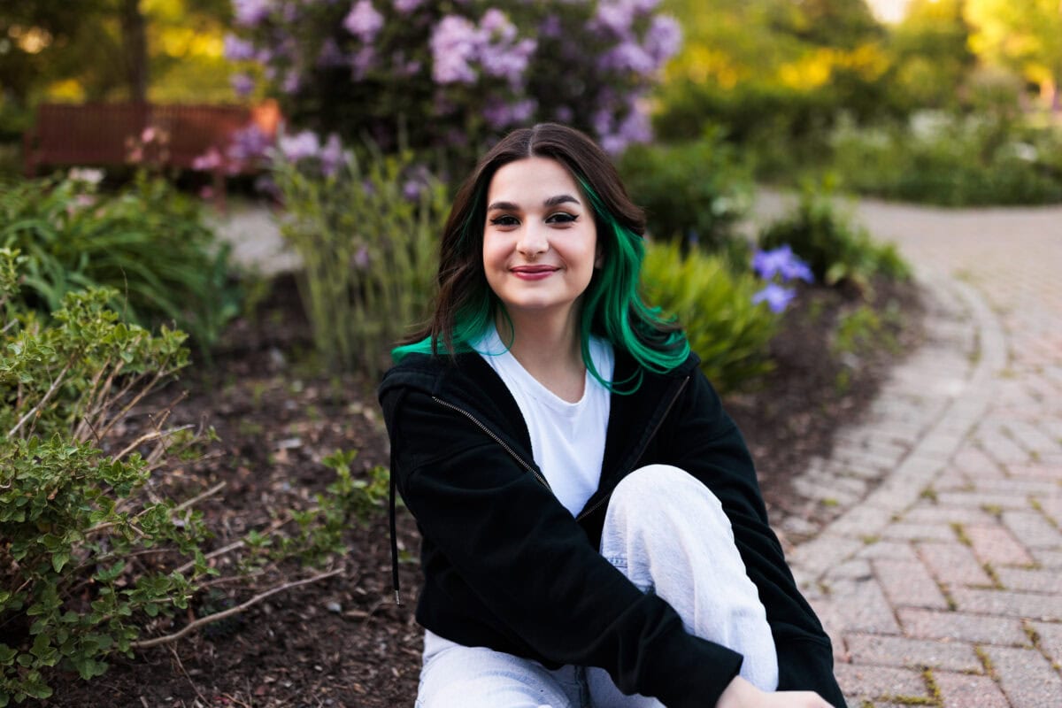smiling senior girl sitting in garden flowers