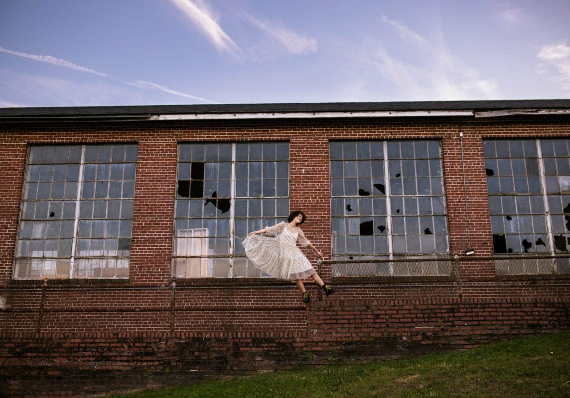 Senior girl on brick wall with building windows in background